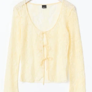 Ljusgul spetsblus med knyt - Säljer en ljusgul, transparent spetsblus från Gina med långa ärmar och knyt framtill. Blusen har v-ringning och är tillverkad i ett tunt, blommigt spetsmaterial och är superfin till allt. NYKÖPT OCH EJ ANVÄND. 