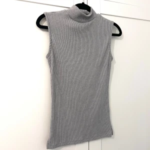 Grå ribbad polotopp - Säljer en grå ribbad polotopp utan ärmar. 