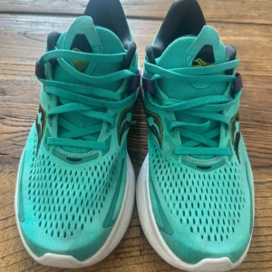 Turkosa löparskor från Saucony - Säljer ett par turkosa Saucony sneakers med vit sula och svarta samt lila detaljer. Skorna har ventilerande mesh-ovandel och snörning. Perfekta för löpning eller träning, med bekväm och stötdämpande PWRRUN-sula. Använda 2 gånger nypris 1600:-