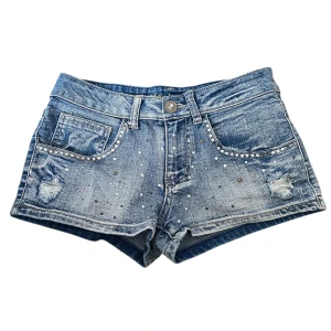 Mörkblå bleached lowrise jeans shorts med rhinestones💙 - Jätte fina korta shorts perfekta för sommaren. I väldigt bra skick, förutom att några rhinestones har lossnat (se bilderna), men det syns knappt. Skriv vid frågor❕  Inga bilder på tyvärr💔 MÅTT Midjemått: 35cm Midjehöjd: 20cm Fraktas alltid samma eller dagen efter köpet!   Vill du slippa frakten eller kika på liknande plagg? Kom gärna förbi Karlaplan loppisen den 12/7!💋 
