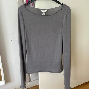 Grå långärmad topp från bik bok - Säljer en enkel och stilren grå långärmad topp från bik bok. Toppen har en rak passform, rundad halsringning och är tillverkad i ett mjukt bomullsmaterial. Perfekt till jeans eller kjol!