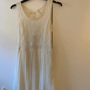Vit klänning från Vero Moda - Superfin vit klänning från Vero Moda med spets upptill. Ärmlös modell med rund halsringning och öppen rygg med knyt. Perfekt till sommarens alla tillfällen! Kontakta för frågor eller prisförslag!