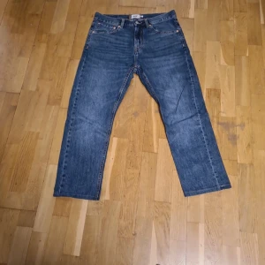 Blå jeansbyxor från Lager 157 - Klassiska blå jeansbyxor från Lager 157 med raka ben och normal passform. Byxorna har fem fickor, gylf med dragkedja och knapp samt tydliga kontrastsömmar. Perfekta för en avslappnad stil. OBS! JAG HAR KORTAT NER BYXORNAS LÄNGD. FRÅGA OM MÅTT.