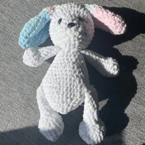 virkad hund - Bilderna visar en virkad hund med mjuk, fluffig textur och pastellfärgade öron (ett blått och ett rosa). Detta är en handgjord virkad gosedjur 