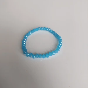 Blått glittrigt pärlarmband - Snyggt armband med facetterade blå pärlor som ger ett glittrigt intryck. Elastiskt band gör det enkelt att ta på och av. Perfekt accessoar för att addera färg till din outfit.