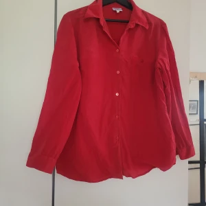 Röd skjorta, Town - röd skjorta från Town i storlek 44. Skjortan har lång ärm, bröstficka och knäppning framtill med matchande röda knappar. 