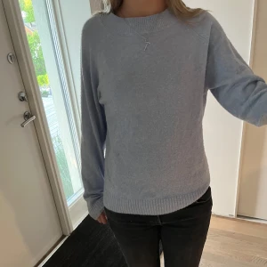 Ljusblå stickad tröja - Mysig ljusblå stickad tröja med rund halsringning och långa ärmar. Tröjan har ribbade muddar vid ärmslut och nederkant, perfekt för kyligare dagar. Enkel och stilren design som passar till det mesta.