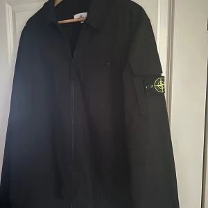 Svart jacka från Stone Island - Säljer en svart tunnare jacka perfekt till sommarkvällarna. Jackan har dragkedja framtill, klassisk krage och ikonisk logotyp på ärmen. Säljer pga den är lite för stor… Nypris: 4700
