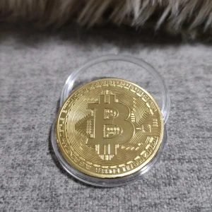 Bitcoin-inspirerad guldmynt - Coolt samlarmynt i guld-look med Bitcoin-symbol på framsidan och detaljerat kretskortsmönster på baksidan. Myntet är runt och levereras i ett genomskinligt plastfodral. Perfekt för dig som gillar krypto och vill ha något snyggt att visa upp. Tillverkat i metall.