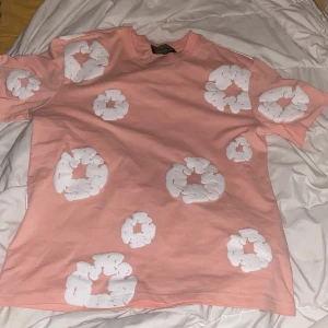 Denim Tears T-shirt  - Säljer en riktigt fet rosa t-shirt från denim tears, har använt ett par fåtal gånger, passar inte min stil längre det är därför jag säljer, perfekt inför sommaren. Nypris 349 men kan komma prisförslag