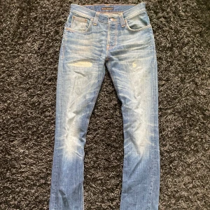 Blå Nudie Jeans - Sjukt feta och unika blå Nudie Jeans med slitningar och snyggt tvättad look!! Jeansen har en liten defekt i grenen, inget som är synbart när dom är på. Hör av er vid funderingar t.ex. fler bilder osv. (Pris kan diskuteras vid snabb affär!!)🤝🤩