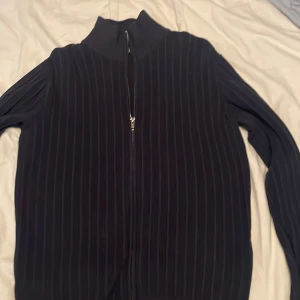Svart ribbad zip-tröja från Dressmann - Ny skick andvänd någon gång bara Säljer en mörkblå ribbad tröja från Dressmann i storlek S. Tröjan har dragkedja framtill, hög krage och långärmade ärmar. Perfekt för lager-på-lager och enkel att matcha med olika outfits.