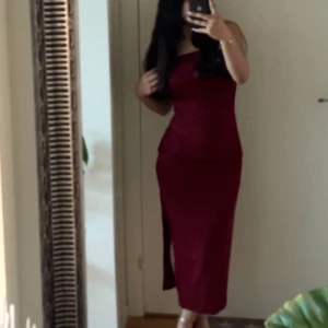 Vinröd långklänning med straps - Säljer en elegant vinröd långklänning med straps-design. Klänningen har en tight passform och är perfekt för festliga tillfällen. Materialet är mjukt och följsamt, vilket ger en snygg siluett.