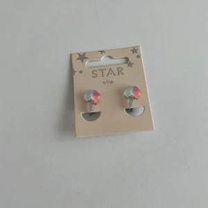 Färgglada örhängen med klämma från Star - Säljer ett par söta örhängen med klämma från Star. Örhängena har glittriga pärlor i pastellfärger som rosa, blå och grön. Perfekta för dig som vill ha örhängen utan hål!