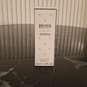 Hugo Boss Woman Eau de Toilette 30 ml - Elegant parfym från Hugo Boss i en stilren, rektangulär glasflaska med ljusrosa ton och silverfärgad, geometrisk kork. Doften är feminin och modern, perfekt för dig som gillar fräscha och blommiga toner. Flaskan rymmer 30 ml Eau de Toilette.