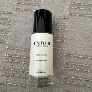 Oöppnad Face Cream från Under Your Skin - En ansiktskräm från Under Your Skin i en stilren vit flaska med svart lock. Produkten är märkt som 'Face Cream' och är både boosting och calming. Passar alla hudtyper och innehåller 50 ml. Nypris: 560kr.