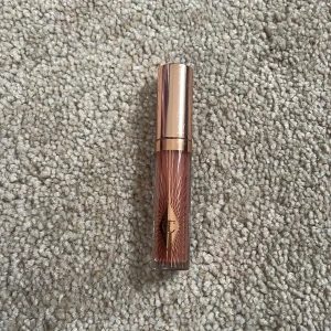 Charlotte Tilbury Pillow Talk läppglans - Säljer ett lyxigt läppglans från Charlotte Tilbury i nyansen Pillow Talk. Kommer i en snygg roséguldig tub med märkets logga och dekorativa linjer. Ger en naturligt rosa ton till läpparna och har en glansig finish.