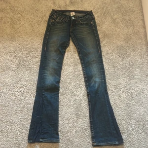 Mörkblå bootcut jeans från True Religion - Säljer ett par mörkblå bootcut jeans från True Religion. Då jag inte har någon användning av dom😊klassiska kontrastsömmar och snygga detaljer på bakfickorna. Jeansen har låg midja och är tillverkade i denim.💕