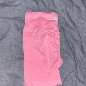 Rosa seamless shorts från DFYNE - Säljer ett par rosa seamless shorts från DFYNE med hög midja och scrunch-detalj bak. Stretchigt material som passar perfekt till träning. Bekväm passform och snygg design.