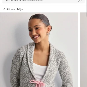 Gråvit stickad kofta från Nelly - Superfin gråvit stickad kofta med diskret mönster och en söt rosa rosett i midjan. Koftan har lång ärm och en mysig krage, perfekt att slänga på sig över ett linne eller t-shirt. Den är från Nelly, i helt nyskick, ord pris 499 mitt pris 250😇