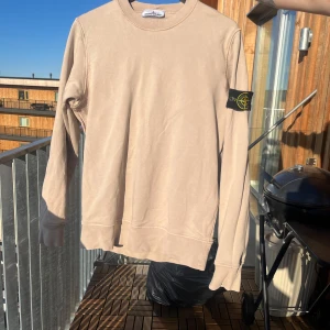 Beige sweatshirt från Stone Island - Säljer en beige sweatshirt från Stone Island med klassisk rund hals och den ikoniska loggan på vänster ärm. Sparsamt använd. Nypris 3000kr