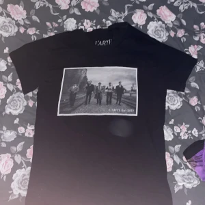T-shirt med tryck  - Svart t-shirt från L'ARTE med ett stort svartvitt tryck. Den är använd men har inte några fel på sig. 