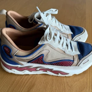 Beige och blå sneakers från Sandro Paris - Säljer ett par snygga sneakers från Sandro Paris i beige, blått och rött med vita snören . Nypris är 2800 sek. Sparsamt använda. 