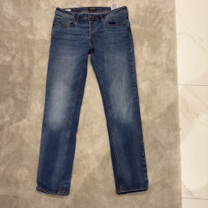 Blå jeans från Jack & Jones - Klassiska blå jeans från Jack & Jones med raka ben och femficksmodell. Jeansen har snygga slitningar och kontrastsömmar. Passar perfekt till vardags och har en tidlös look med normal passform.