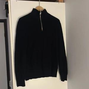Mörkblå stickad tröja med dragkedja från H&M - Säljer en mörkblå stickad tröja från H&M med halv dragkedja och hög krage. Slim fit-modell som passar perfekt till vardags. Klassisk och stilren design med långa ärmar. Använt få gånger