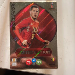 Panini Adrenalyn XL Limited Edition Eden Hazard - Säljer ett samlarkort från Panini Adrenalyn XL-serien, Limited Edition med Eden Hazard från Belgien, FIFA World Cup Russia 2018. Kortet har glänsande röd bakgrund och visar spelaren i landslagströja. Perfekt för samlare av fotbollskort.