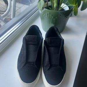 Svarta sneakers från Axel Arigato - Svarta Clean 90 laceless från Axel arigato i storlek 37. Använd fåtal gånger så de är fortfarande i toppskick, fin häl och sula.