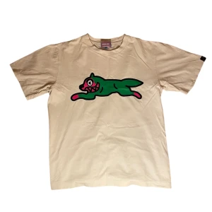 BBC t-shirt - Säljer en vit t-shirt från Billionare Boys Club med en stor grön tecknad katt på bröstet och en liten röd logga i nacken. T-shirten har en avslappnad passform och är tillverkad i mjuk bomull. Perfekt för dig som gillar streetwear och unika prints.    T-shirten har dock några små hål i ryggen (se bild tre) vilket är förklaringen till det låga priset. Storleken är igenkligen M men passar S mer.