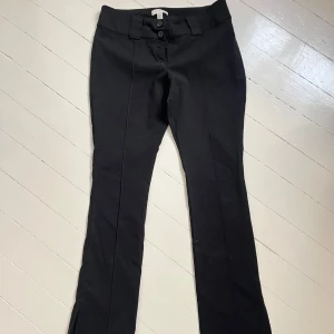 Svarta kostymbyxor med bootcut - Snygga medelhöga svarta kostymbyxor med bootcut och pressveck. Byxorna har två knappar i midjan, bälteshällor och klassisk passform. Perfekta för en stilren look och passar till många olika outfits. Skriv för fler bilder💞