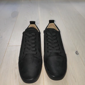 Christian Louboutin I 42 passar för 43 I Ej använda  - Säljer ett par svarta sneakers från Christian Louboutin med klassisk röd sula och ovandel i mocka. Skorna har rund tå, svarta snören och diskret logga på sulan. Perfekta för dig som gillar stilrena och exklusiva sneakers. OBS!! ingen box