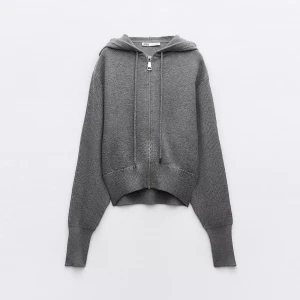 Grå stickad hoodie med dragkedja zara - Säljer en grå stickad hoodie med dragkedja framtill och huva. Tröjan har långa ärmar och ribbade muddar. Perfekt för lager-på-lager och chill dagar.