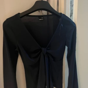 Mörkblå långärmad topp med knyt  - Säljer en mörkblå långärmad topp från gina med snygg knytning framtill. Toppen har en djup v-ringning och är tillverkad i ett mjukt material som sitter skönt på kroppen. Har haft på mig Max 4 gånger men kommer inte mer till användning. Skriv för fler bilder eller frågor💗