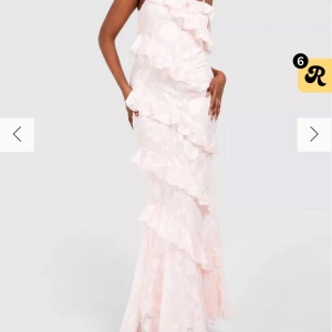 Ljusrosa långklänning med volanger från Boohoo - INTRESSEKOLL!!💕Supersöt ljusrosa långklänning från Boohoo med volangdetaljer och ett axelbandslöst snitt på ena sidan. Klänningen har ett romantiskt uttryck med blommigt mönster i tyget och smala axelband. Perfekt för speciella tillfällen!