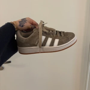 Adidas Campus 00s Beige - Säljer ett par Adidas Campus sneakers som är blöta då jag precis rengjort de, inga större defekter bara att ”mockan” luddat sig efter att de rengjorts. Sulan är kritvit, undersidan är jätteren. Köpt för 1250kr på JD sports, nypris idag är 1100kr. Kan sänka pris vid snabb affär💕🫶🏻