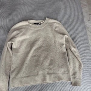 Beige stickad tröja från Vero Moda - Säljer en enkel och stilren beige stickad tröja från Vero Moda i storlek XS. Tröjan har rund halsringning, långa ärmar och ribbade muddar vid ärmslut och nederkant. Perfekt för lager-på-lager under kyliga dagar.