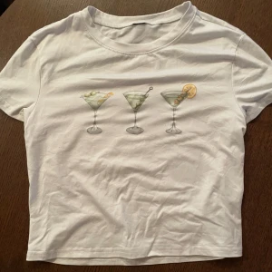 Vit t-shirt med martiniglas-tryck - Vit t-shirt med snyggt tryck på bröstet. Säljer på grund av att den ej kommer till användning.