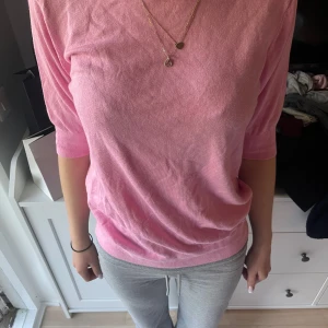 Rosa stickad tröja med trekvartsärm - Säljer en ljusrosa stickad tröja med trekvartsärmar. Tröjan har en rund halsringning och är mjuk och tunn i materialet, perfekt för lager-på-lager. Enkel och stilren design som passar till mycket.