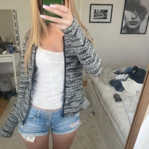 Gråmelerad stickad cardigan - Mysig gråmelerad stickad cardigan med dragkedja framtill. Koftan har lång ärm och en avslappnad passform. Perfekt att slänga på sig över en t-shirt för en chill look.