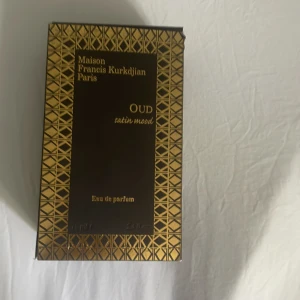 Maison Francis Kurkdjian Oud Satin Mood Eau de Parfum - Lyxig parfym i elegant svart och guldig förpackning från Maison Francis Kurkdjian Paris. Doften heter Oud Satin Mood och är en Eau de Parfum. Förpackningen har geometriskt mönster i guld och svart med exklusiv känsla. Endast testad. Kom med bud 