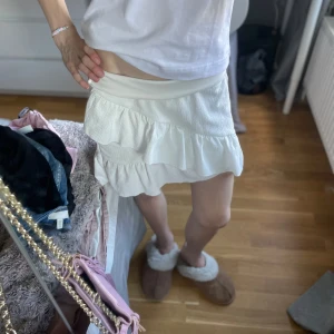 Vit volangkjol - Superfin vit kjol med volangdetaljer och kort längd. Kjolen har en lätt struktur i tyget och sitter normalt i midjan. Perfekt för en fräsch och somrig look. 