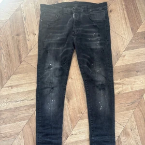 Dsquared2 jeans  - Svarta jeans med skinny passform och slitna detaljer samt vita färgstänk. Jeansen har klassisk femficksdesign och dragkedjegylf. Perfekta för en trendig och avslappnad look. Kom med pris förslag eller frågor