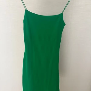 Grön klänning med smala axelband från Zara - Säljer en snygg grön klänning från Zara med smala axelband och rak passform. Klänningen är enkel och stilren, perfekt för dig som gillar minimalistisk stil. Materialet känns mjukt och följsamt.