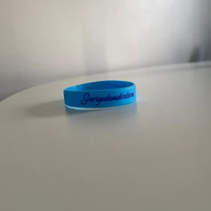 Sverigedemokraterna armband  - Blått silikonarmband med texten 'Sverigedemokraterna' i svart. Perfekt som accessoar för dig som vill visa ditt stöd eller samla på politiska armband.