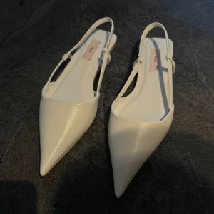 Vita spetsiga ballerinaskor från Nelly - Säljer ett par vita ballerinaskor/pumps från Nelly utan klack. Oanvända strl 37. Låda medföljer🤍