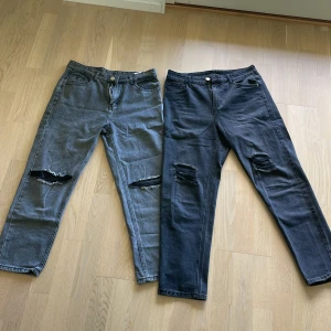 Två par jeans i grå och svart - Säljer två par raka jeans, ett i grått och ett i svart, båda med produktionsgjorda slitningar över knäna. Klassisk femficksmodell med knapp och dragkedja. Perfekta för en avslappnad och trendig look. Går även att bara köpa ett par om man är sugen (100 kr styck) 