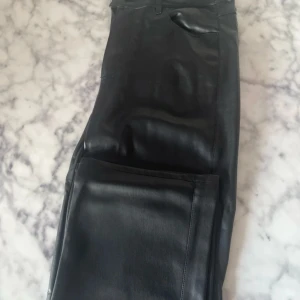 Svarta skinnbyxor - Snygga svarta byxor i skinnimitation. Byxorna har en rak passform. Använda ett fåtal gånger. 